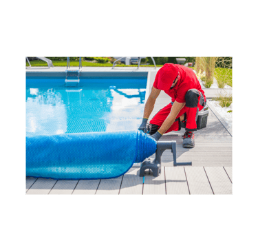 Pool tech in red uniform kneeling poolside getting ready to unroll the pool cover