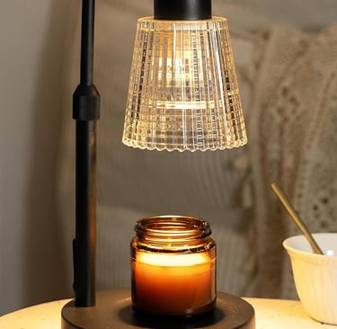 Black electric candle warmer lamp with amber jar candle and ribbed glass shade on a cozy bedside tab