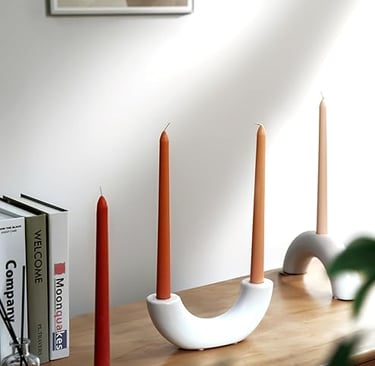 Modern white ceramic candle holders with burnt orange taper candles on wooden console table