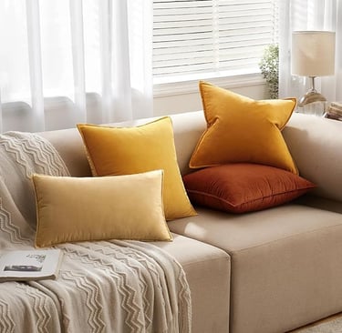 Cozy beige couch with mustard yellow, burnt orange, and cream velvet throw pillows