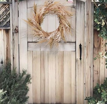 Neutral fall wreath made of dried wheat and grasses hanging on a wooden garden gate