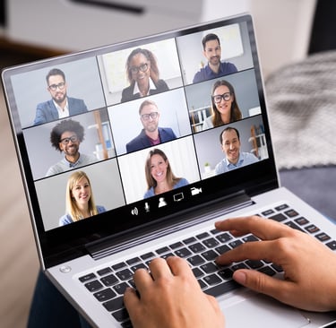 A person with a laptop participating in a virtual team meeting
