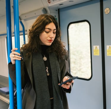 A woman standing in a train car, looking at her smartphone