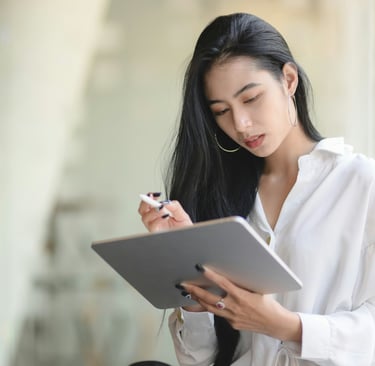 A young businesswoman using a digital tablet while standing in a modern office.