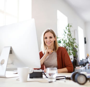 A young, blonde businesswoman sitting in a wheelchair, working at her desk.