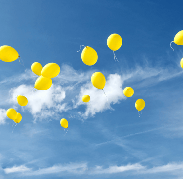 Cielo azzurro limpido con palloncini gialli che volano via, simbolo del lasciare andare, di libertà