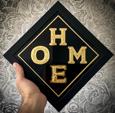 chipped glass lettering sign with gold leaf, black background and frame