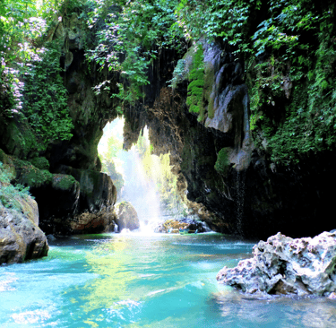 a waterfall flowing down a river with a boat in the background