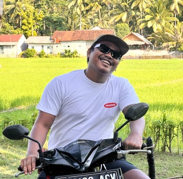 Ucup on motorbike with rice paddy in background