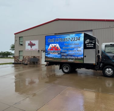 Digital mobile billboard truck for Arkansas cheer and dance advertising parked in front of a sports facility.