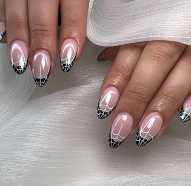 Almond-shaped fall nails with black and white spiderweb tip design.