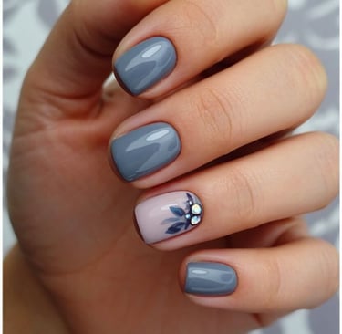 Dusty blue-grey fall nails with navy leaf accents and crystal embellishments.