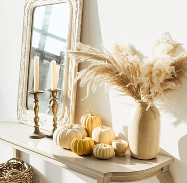 Neutral fall entryway decor with white and golden mini pumpkins, pampas grass in a beige ceramic vas