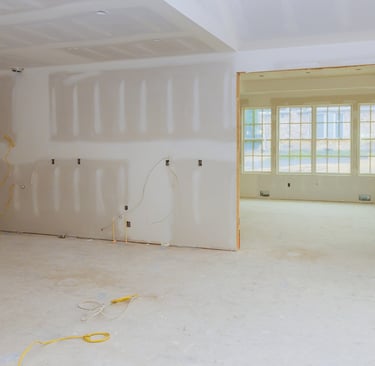 alt="Room under renovation with new drywall and windows after fire damage repair"