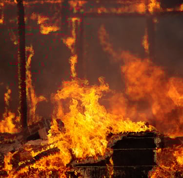 alt="Close-up of active house fire with visible flames and burning debris"