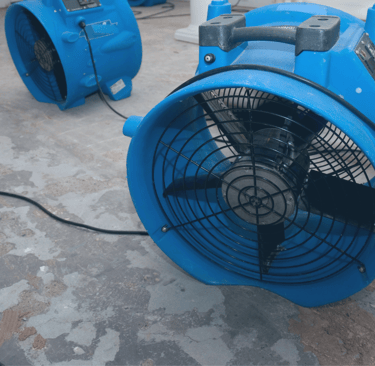 alt="Blue industrial air mover used for drying water damage in residential property"