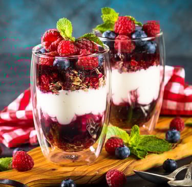 two glasses of yogurt with berries and mint leaves