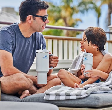 Adulto e criança usando garrafas Stanley em ambiente externo, destacando momentos em família e prati