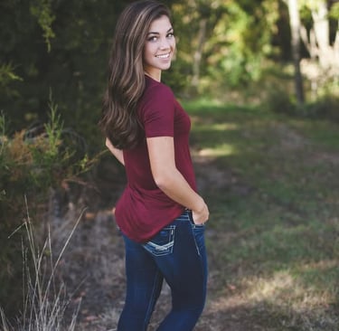 a woman in jeans and a maroon shirt is posing for a photo