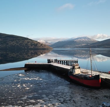 a boat docked on Loch Fyne with mountains in the background