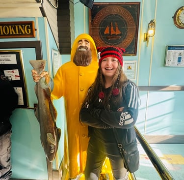 girl standing next to a fisherman statue in a yellow raincoat holding a fish 