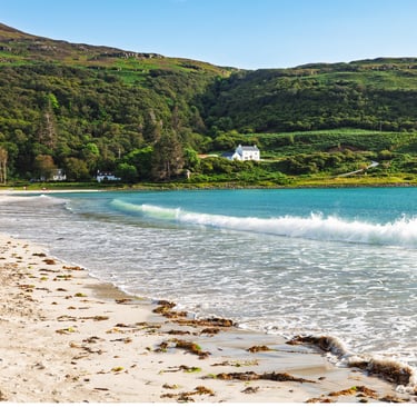 a beach with a house and a green hills