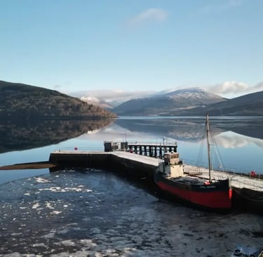 a boat docked on Loch Fyne with mountains in the background