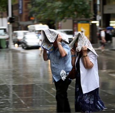 two people with newspapers over their heads in the rain