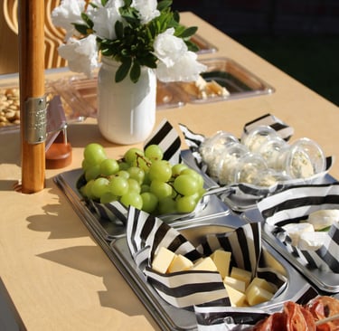 top of a bar cart with charcuterie items in containers and flowers