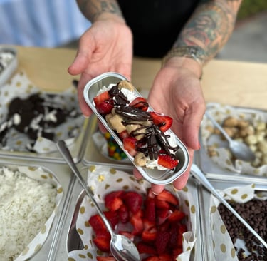 a person holding a dessert over a bar with topping options