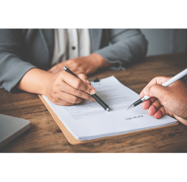 a person holding a pen and writing on a paper