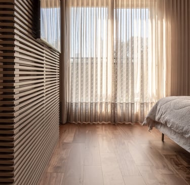 quarto com piso de madeira natural, painel ripado, cama e cortina wave
