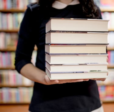 Mulher segurando uma pilha de livros em uma livraria