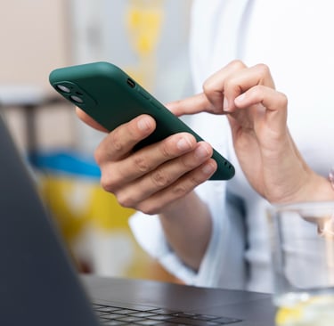 Mão da secretária de um advogado segurando um celular enquanto usa o WhatsApp Business