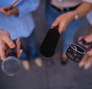 Pessoas segurando microfones ao entrevistar uma pessoa