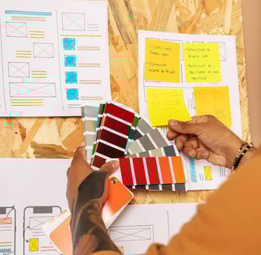 Designer de website com papeís para escolher cores em um mural