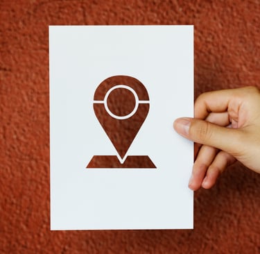 Uma pessoa segurando um papel com o desenho de uma marcação em um mapa
