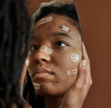 Tamsiaodė mergina su pleistrais ant veido žiūri į veidrodį