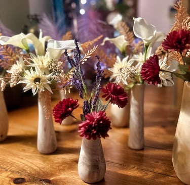 a group of rustic vases with flowers turned from reclaimed tree limbs