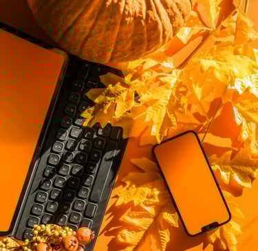 a cell phone and a keyboard on a table with orange leaves