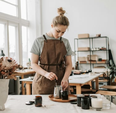 a woman in a brown apron is crafting behind a table