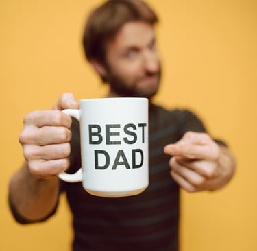 man holding white cup with best dad written on it