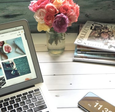 a laptop computer and a cell phone, roses and books on a table