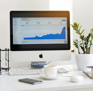 a computer monitor screen showing a graph, a cup of coffee and a plant on a table