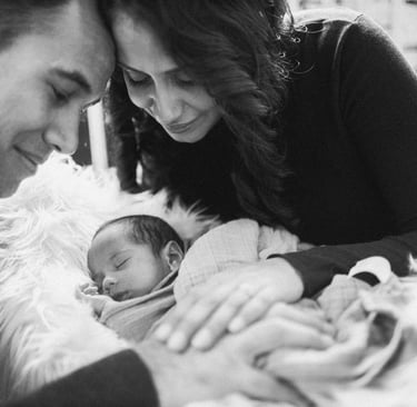 a man and woman holding a baby in a blanket