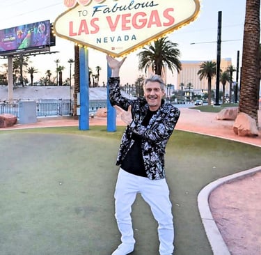 Tim in a floral blazer posing in front of the iconic Welcome to Fabulous Las Vegas Nevada sign.
