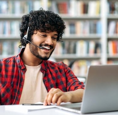 Male student with headset waving in front of laptop