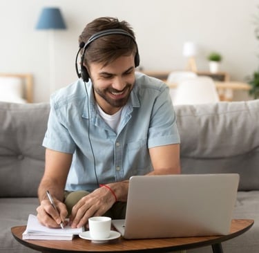 Young man sitting with headset in front of his laptop