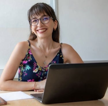 Woman wearing glasses smiling at viewer with laptop
