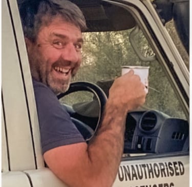 Herve Fritz laughing whilst driving with coffee in hand
